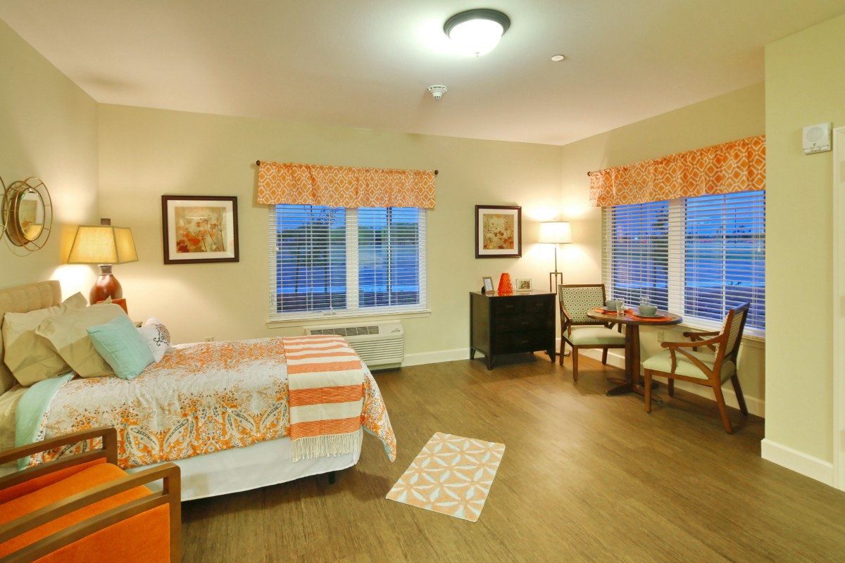 A cozy and well-lit bedroom with stylish decor, featuring large windows and comfortable furniture.