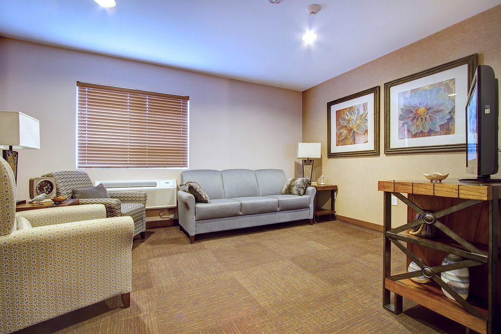A cozy living room with a sofa, chairs, and wall artwork.