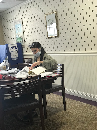 A person reading and studying at a table filled with books in an indoor workspace.
