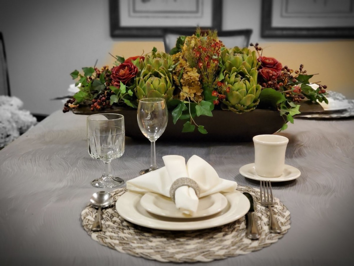 A beautifully set dining table with elegant tableware and a floral centerpiece.