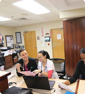 Medical staff collaborating at a hospital workstation.