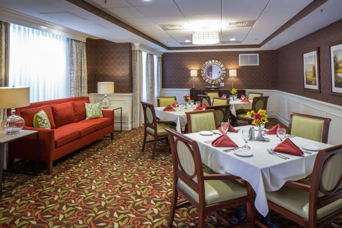A warmly decorated dining room with neatly set tables and comfortable seating.