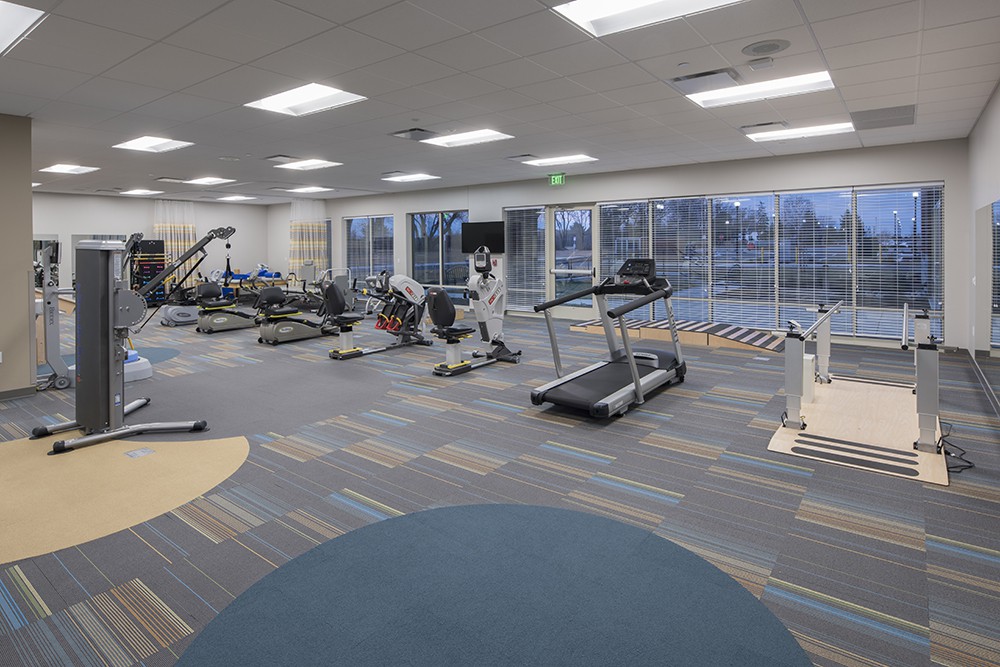 A modern gym with various exercise equipment including treadmills and elliptical machines.