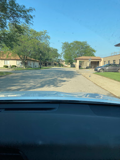 A car's perspective driving through a quiet residential street on a sunny day.