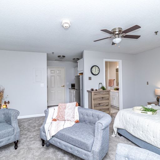 A cozy living area with modern decor featuring a bed, stylish chairs, and light neutral colors.