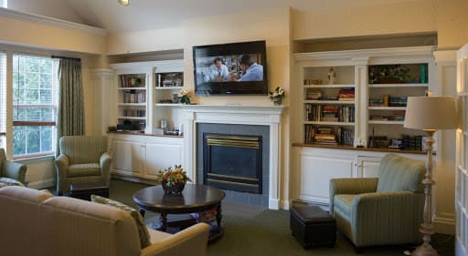 A cozy living room with a fireplace, television, and built-in shelves.