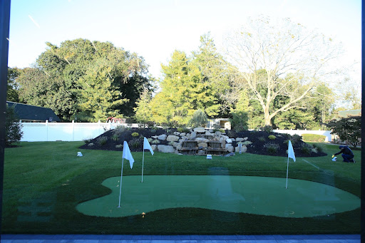 A serene putting green surrounded by lush greenery.