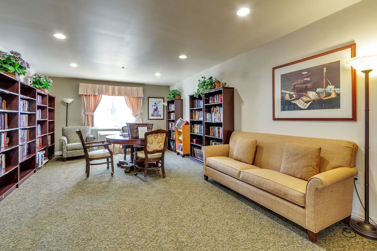 A cozy living room with a sofa, bookshelves, and a table with chairs near a window.