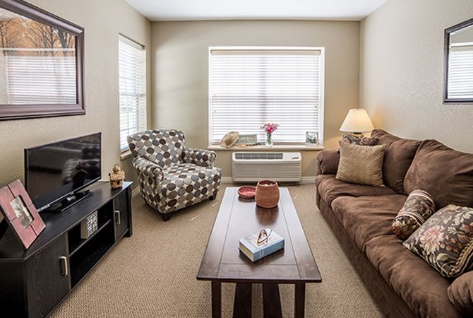 A cozy living room with a sofa, armchair, coffee table, and television.