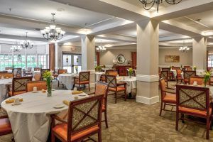 A well-appointed dining room with neatly arranged tables and chairs, featuring elegant lighting and decor.