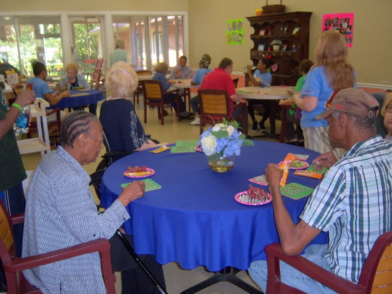 A group of people participating in an indoor social gathering, sitting around tables.