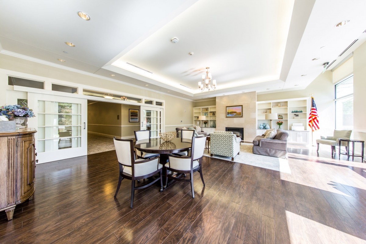 A spacious and modern living room with a dining area, featuring hardwood floors and elegant furniture.