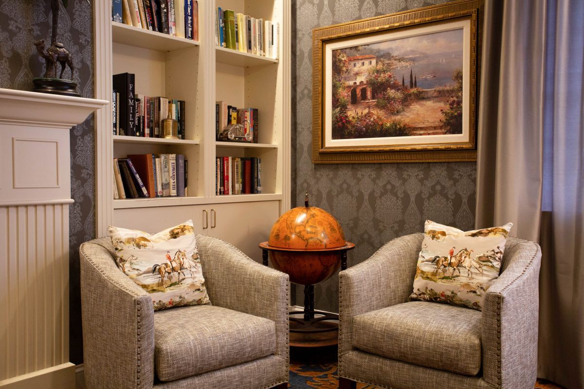 A cozy living room corner with two chairs, a globe, and bookshelves.