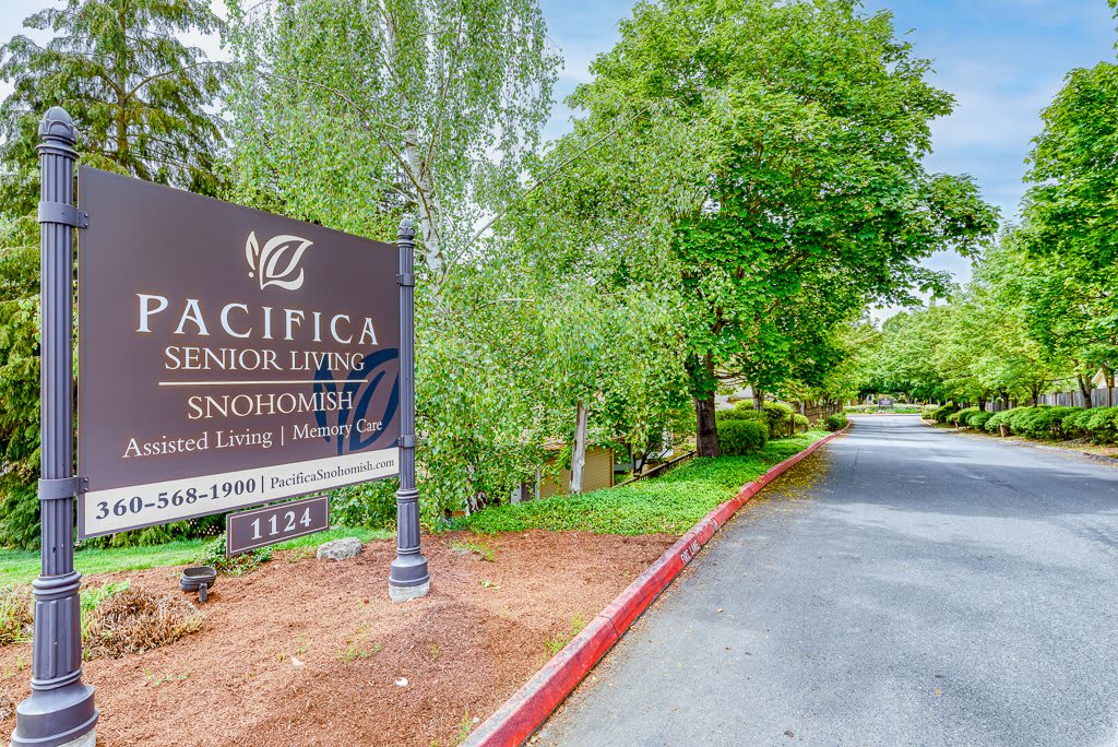 Entrance to Pacifica Senior Living with a welcoming driveway surrounded by lush greenery.