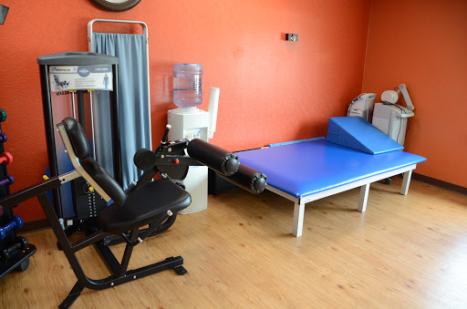 A physical therapy room equipped with exercise machines and a treatment table.