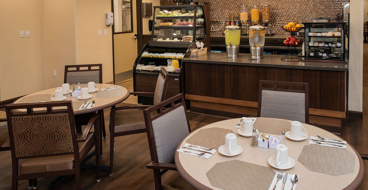 A cozy dining area with neatly set tables and a self-service beverage station.