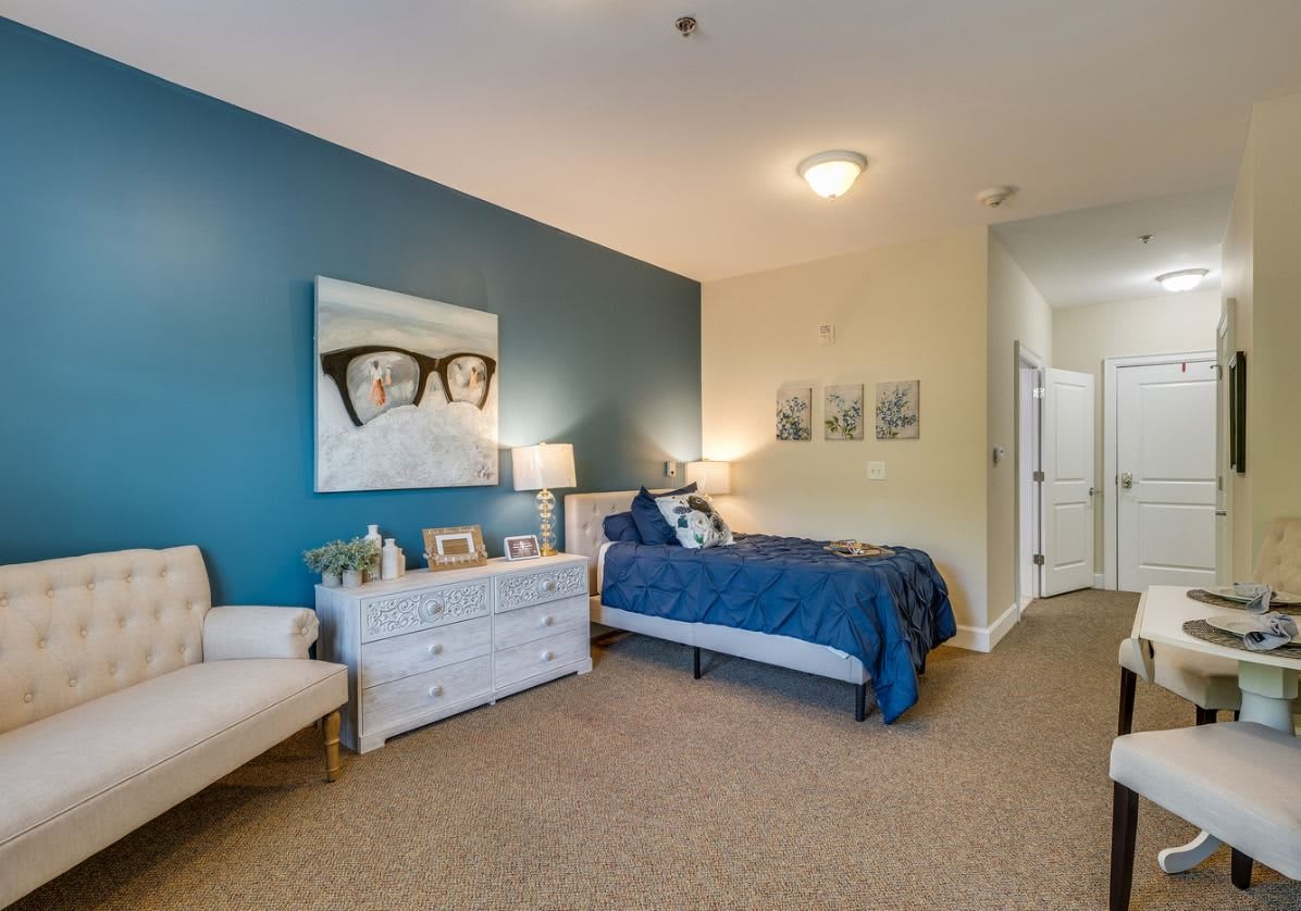A modern bedroom featuring a single bed with a blue accent wall and tasteful decor.