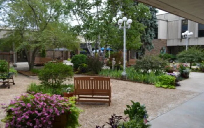 A peaceful garden with a wooden bench, surrounded by lush greenery and colorful flowers.