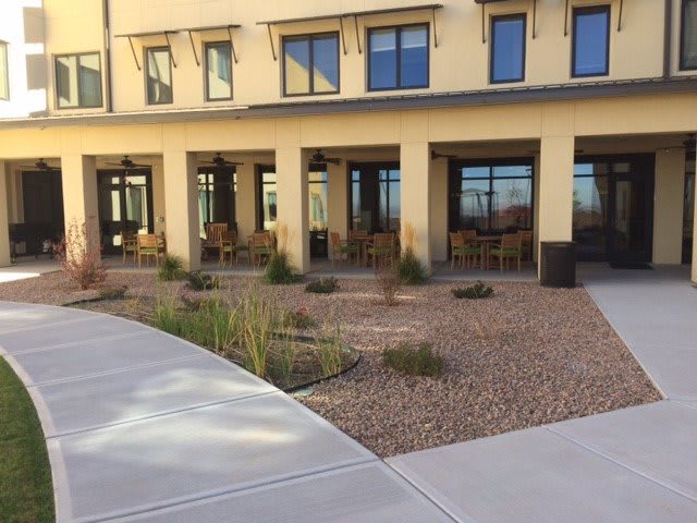 A view of a building with outdoor seating and landscaped surroundings.