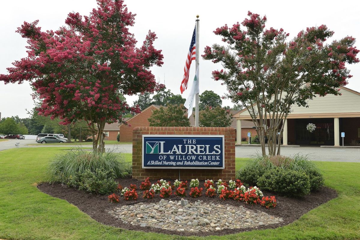 Entrance to The Laurels of Willow Creek with manicured landscaping and an American flag.