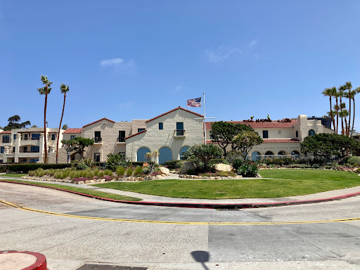 A picturesque building surrounded by lush greenery and palm trees under a clear blue sky.