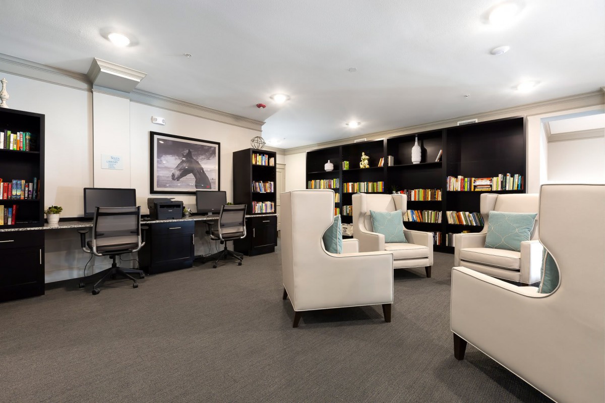 A modern library interior with comfortable seating, bookshelves, and computer workstations.