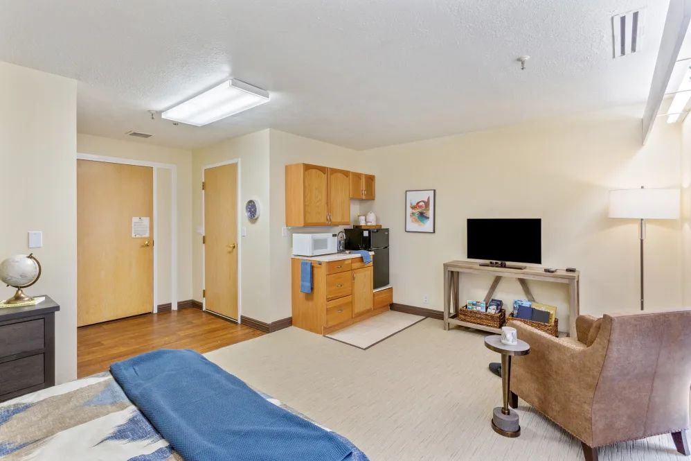 A cozy room with a small kitchenette, TV, and bed area.