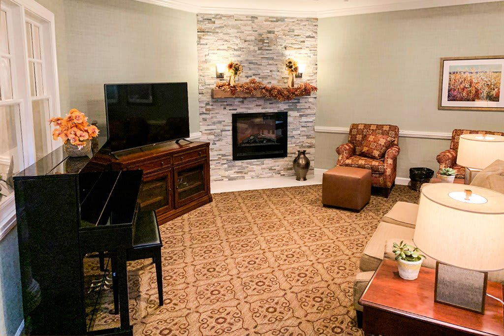 A cozy living room featuring a piano, fireplace, and a comfortable seating area.