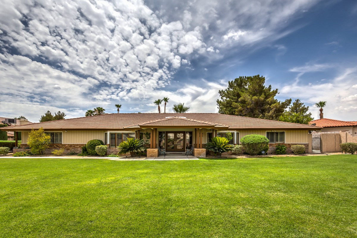 A suburban house with a well-maintained lawn under a cloudy sky.