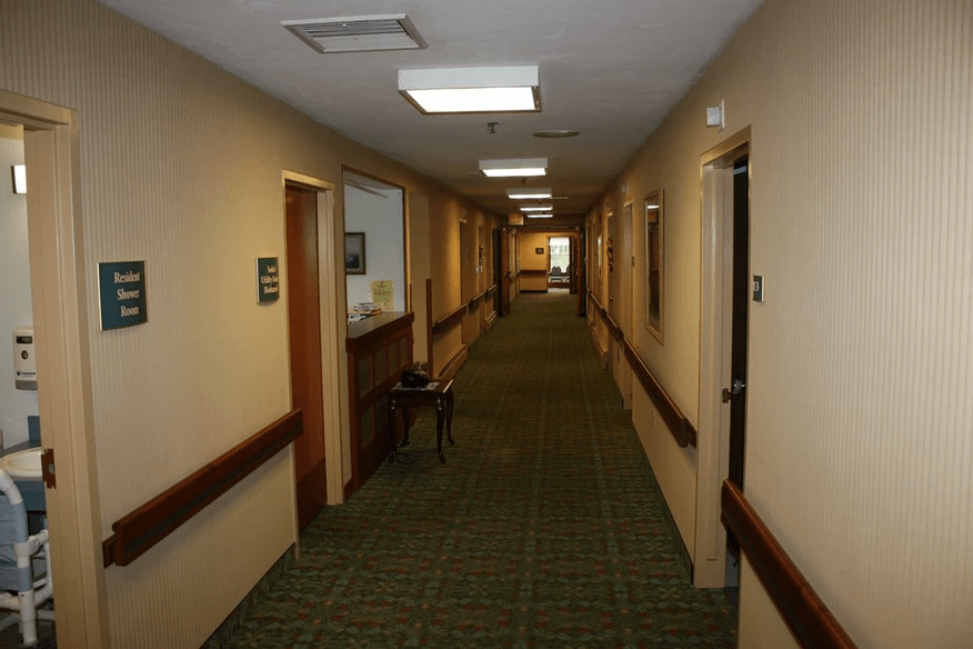 A well-lit corridor with carpet flooring and multiple doors.