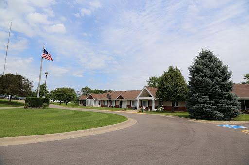 A peaceful residential building with an American flag, surrounded by greenery and a winding road.