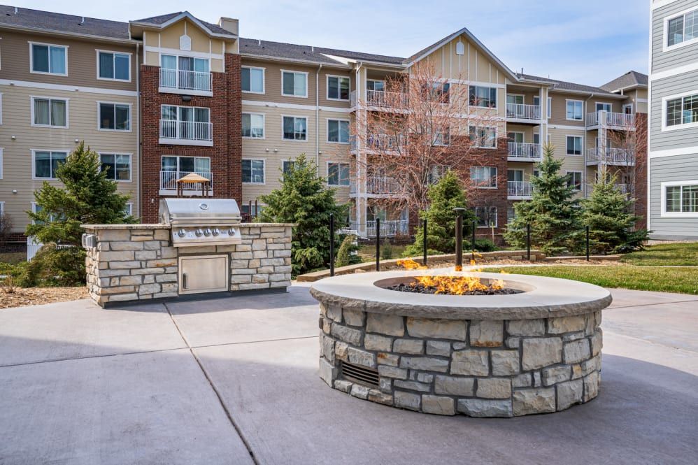 A modern apartment building with a landscaped outdoor area featuring a stone fire pit.