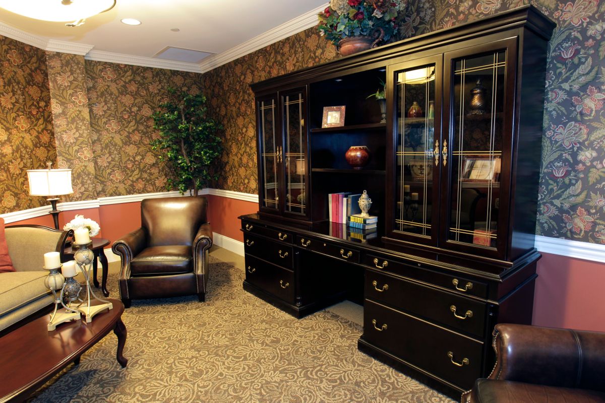 A cozy office space featuring a comfortable chair, large wooden bookshelf, and elegant decor.