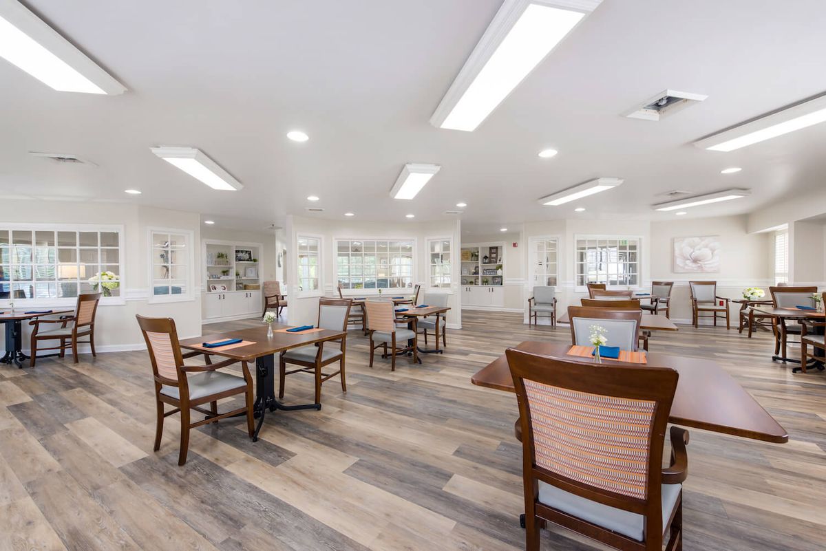 A spacious, well-lit interior with wooden chairs and tables arranged neatly on a polished floor.