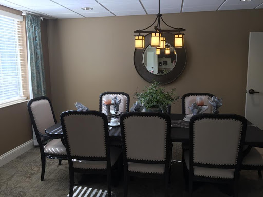 A well-decorated dining room featuring a stylish chandelier, elegant table settings, and a touch of greenery.