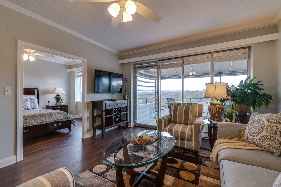 A modern living room with comfortable seating and ample natural light, featuring a glass coffee table and sliding doors leading to a balcony.