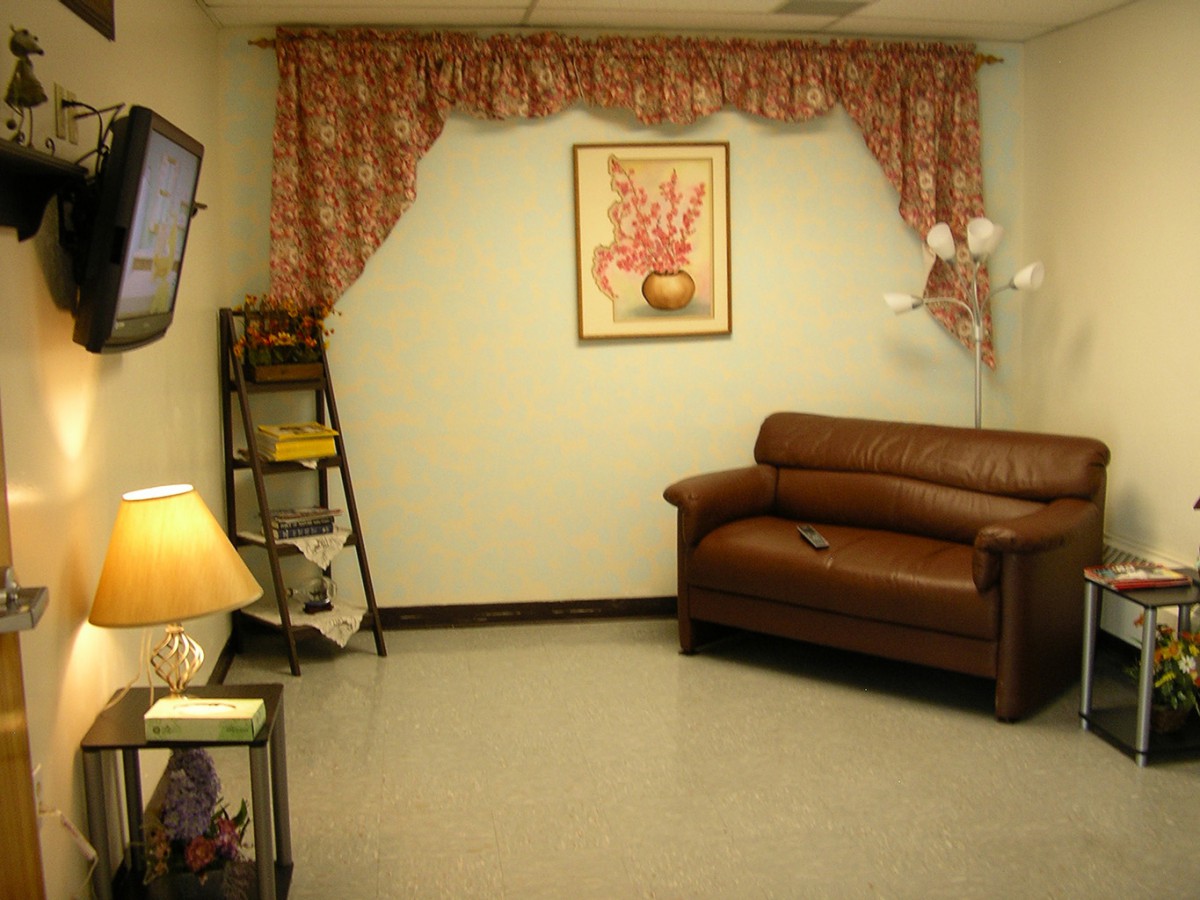 A cozy living room with a brown sofa, a decorative lamp, and a painting on the wall.