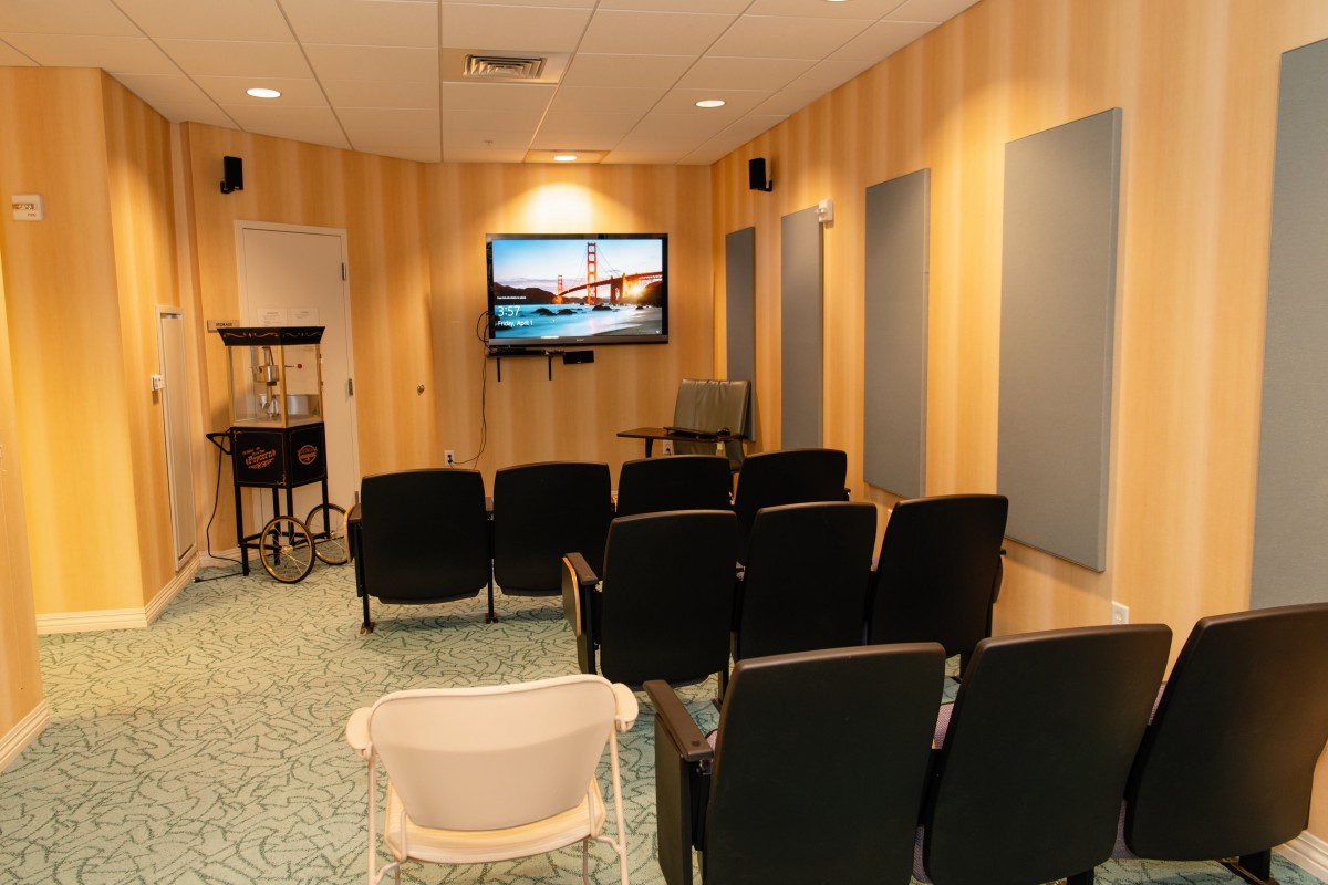 A cozy home theater room with multiple chairs facing a large screen on the wall.