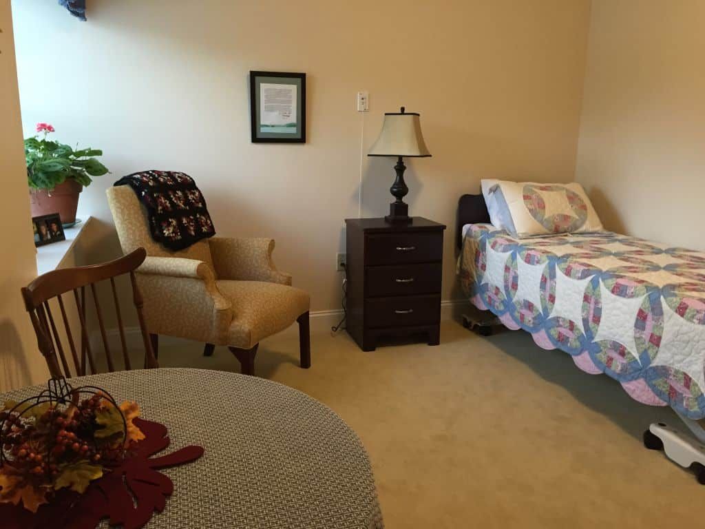 A cozy bedroom with a single bed, nightstand, and comfortable seating.