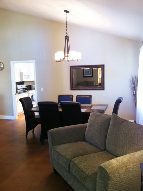 A cozy living and dining area featuring a modern sofa, dining table with chairs, and a decorative chandelier.