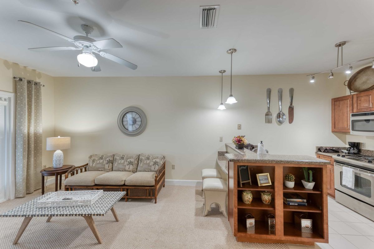 A cozy living space featuring a sofa, coffee table, and a bar area with hanging utensils and pendant lighting.
