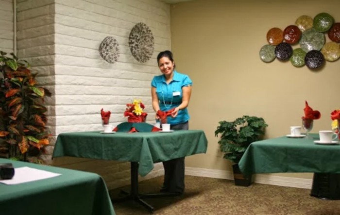 A staff member arranging flowers on tables in a restaurant setting.