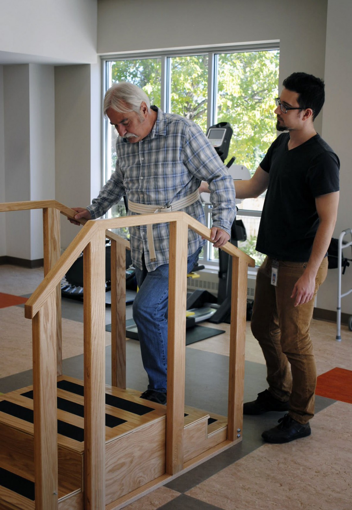 An elderly man receives assistance during a physical therapy session.
