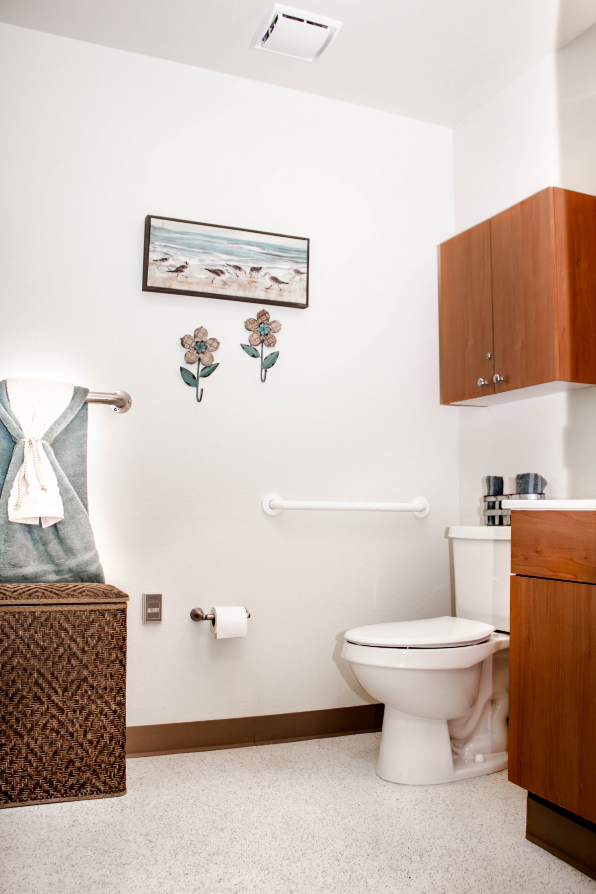 A neatly organized bathroom with a toilet, towels, and wall decor.