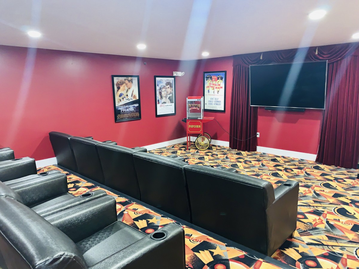 A cozy home theater setup with leather seating, adorned with movie posters on red walls.