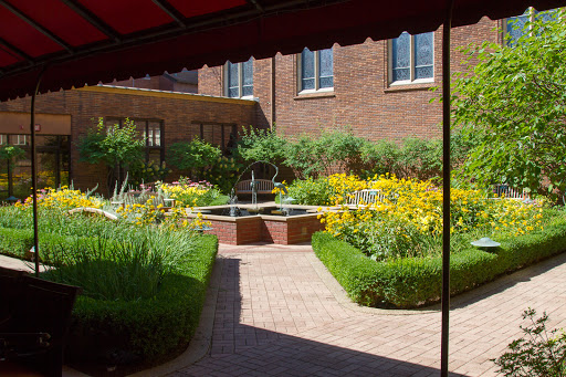 A serene garden featuring a fountain surrounded by vibrant flowers and neatly manicured hedges.