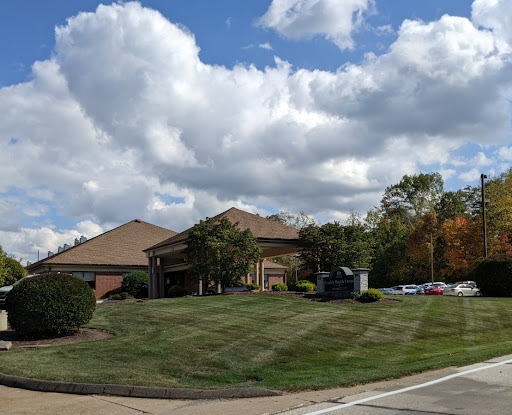 A picturesque scene featuring a building surrounded by lush grass and beautiful clouds in the sky.