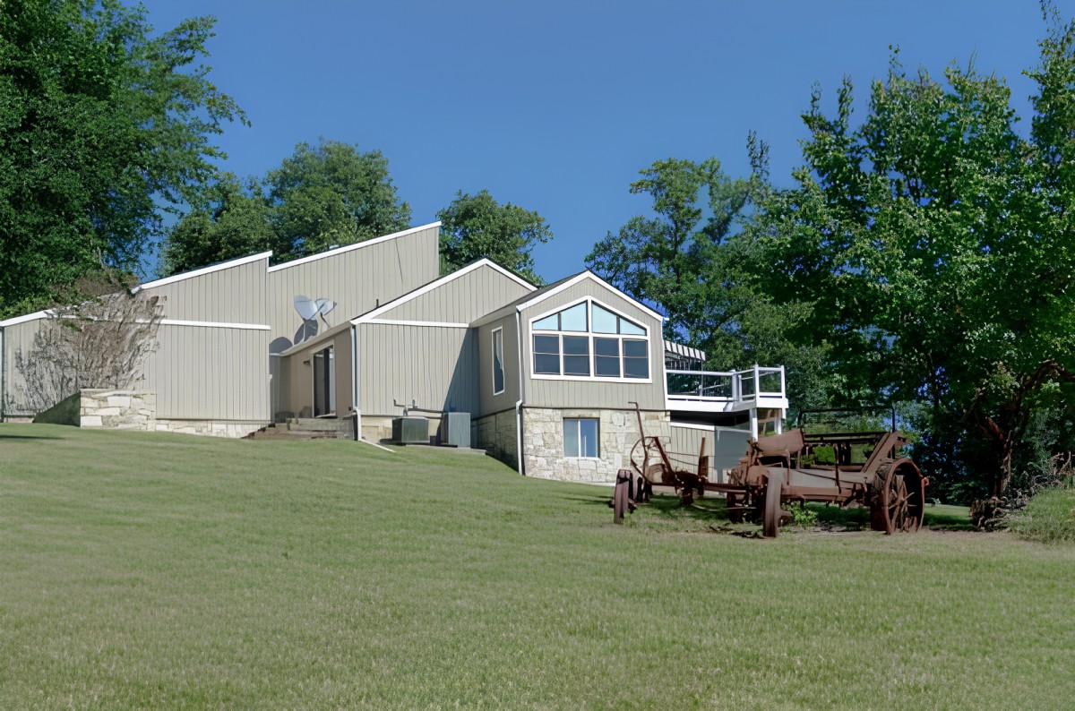 A modern house with large windows and a surrounding lawn on a sunny day.