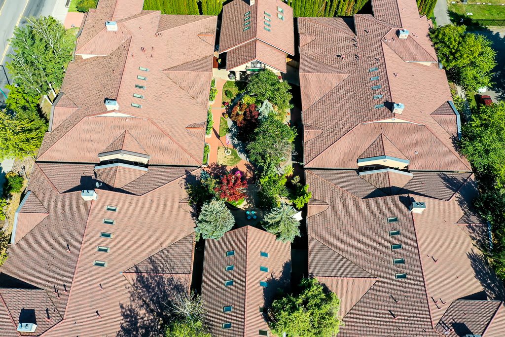 Aerial view of rooftops with a central garden area surrounded by trees in a residential neighborhood.