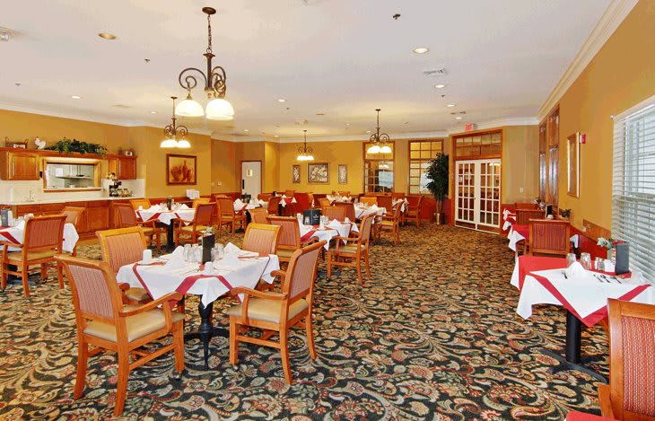 A spacious and elegantly decorated restaurant dining room with neatly arranged tables and chairs.